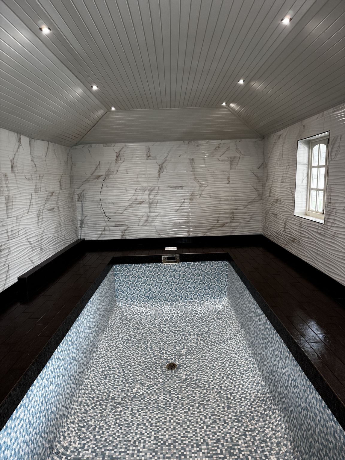 Completed pool room with tiled walls and surround